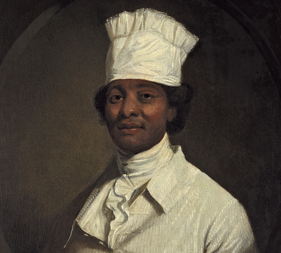African American man wearing all white, including a white cylindrical cook's hat.