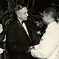 Dr. Berry in formal attire shaking hands with a white man and woman.