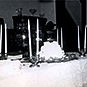 A room with a white lacy table cloth on a long table with tall candlesticks and centerpiece.