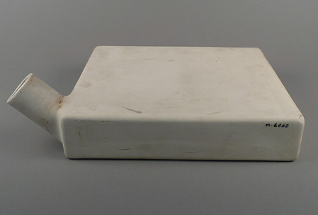 Side view of square-sided, flat ceramic vessel with short cylindrical spout