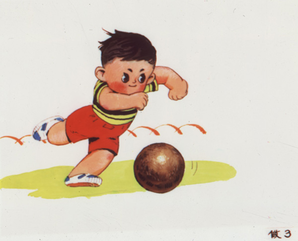 Slide showing a little boy with dark hair, wearing red shorts and a yellow and black shirt, approaching a red ball and pulling back his leg to kick it